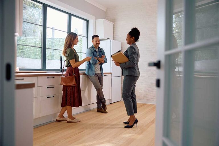 A couple reviews documents together at a kitchen table with moving boxes in the background.