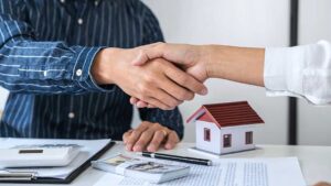 A couple reviews credit reports, bills, and a home budget at a kitchen table.